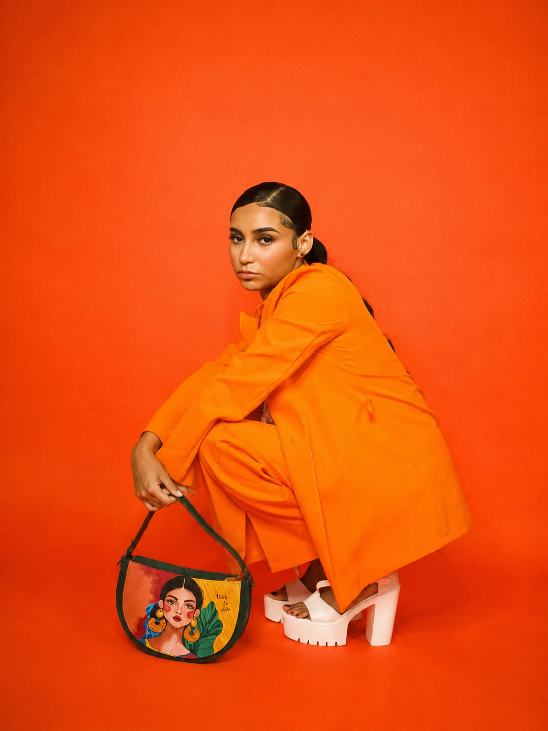 Woman in orange carrying a hand-painted SHARENA bag